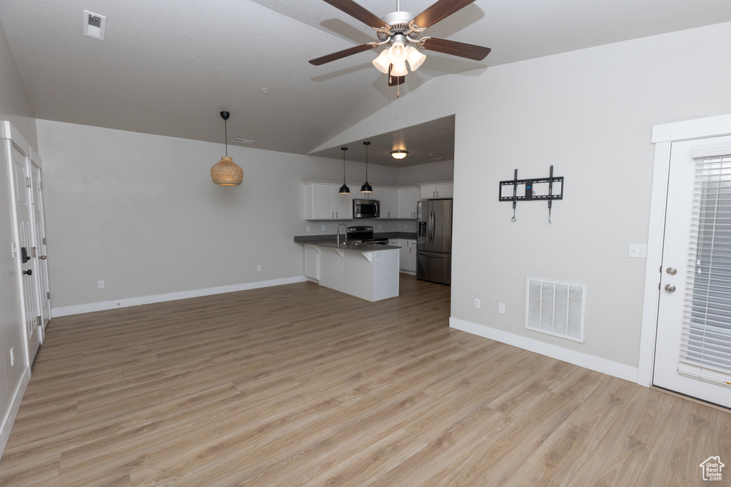 Unfurnished living room featuring lofted ceiling, a ceiling fan, baseboards, light wood-type flooring, and a sink