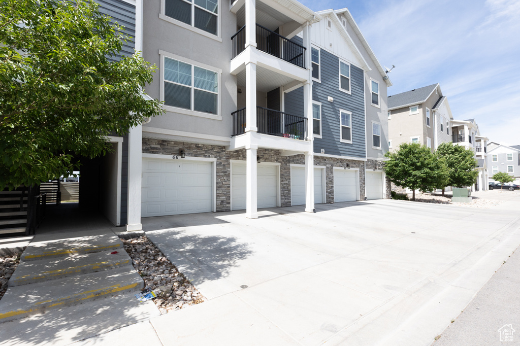 View of building exterior featuring driveway, an attached garage, and a residential view