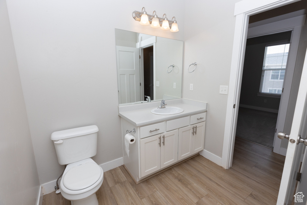 Bathroom with wood finished floors, vanity, baseboards, and toilet