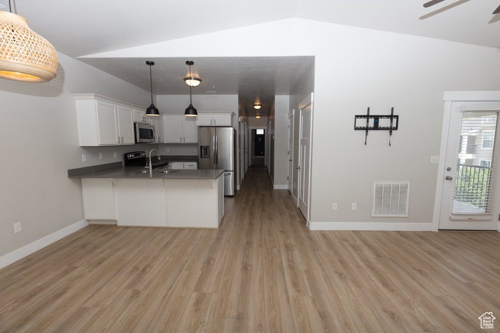 Kitchen featuring stainless steel appliances, a peninsula, light wood-style flooring, white cabinetry, and a sink
