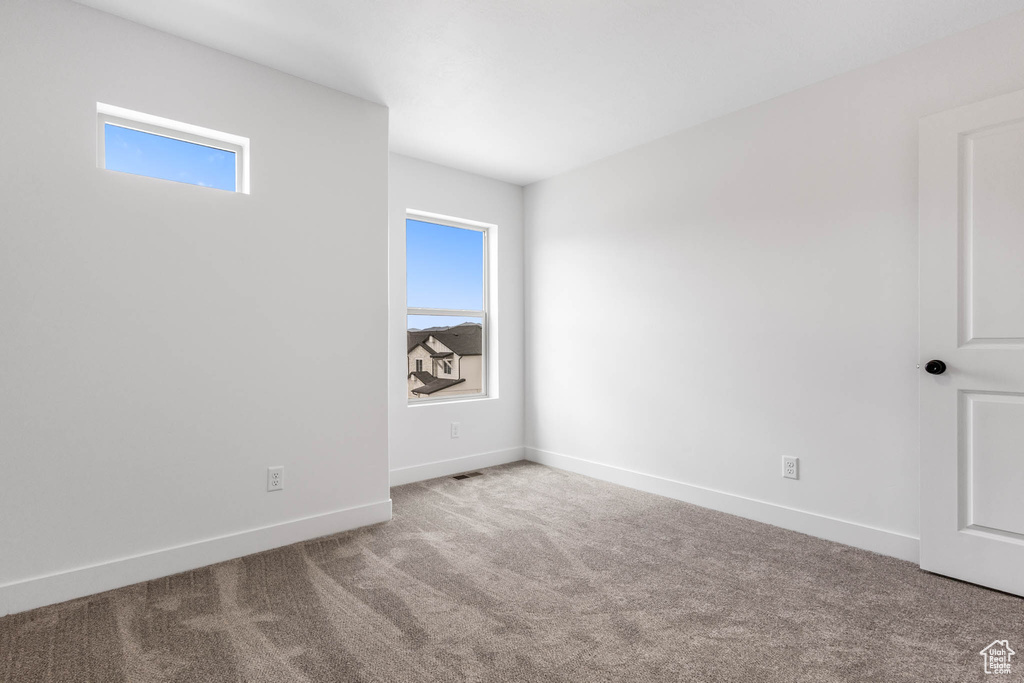 Unfurnished room featuring healthy amount of natural light, carpet, and baseboards