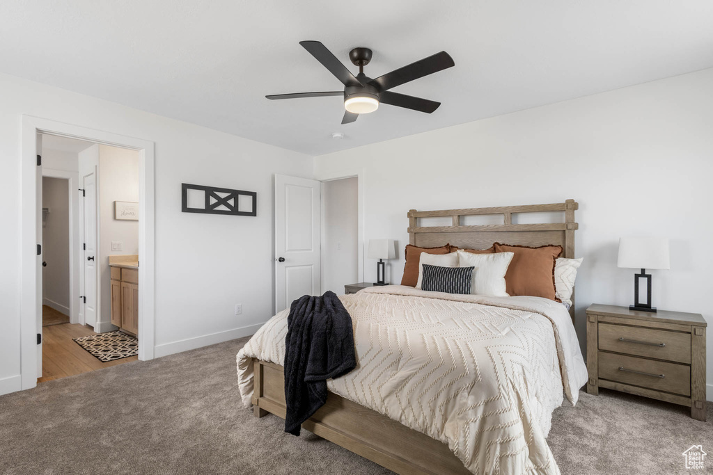 Bedroom featuring light carpet, ensuite bath, baseboards, and ceiling fan