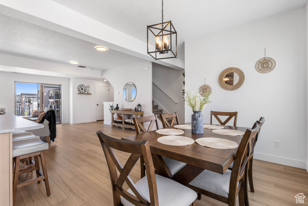 Dining room featuring stairway, light wood finished floors, baseboards, recessed lighting, and a chandelier