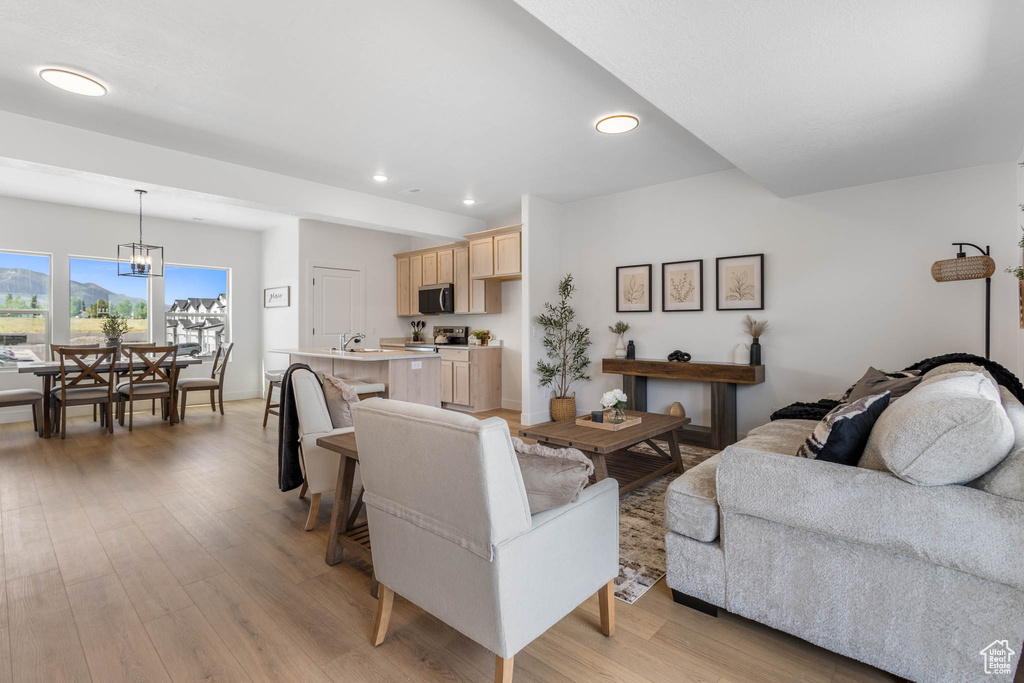 Living room with recessed lighting, light wood-style flooring, and a chandelier