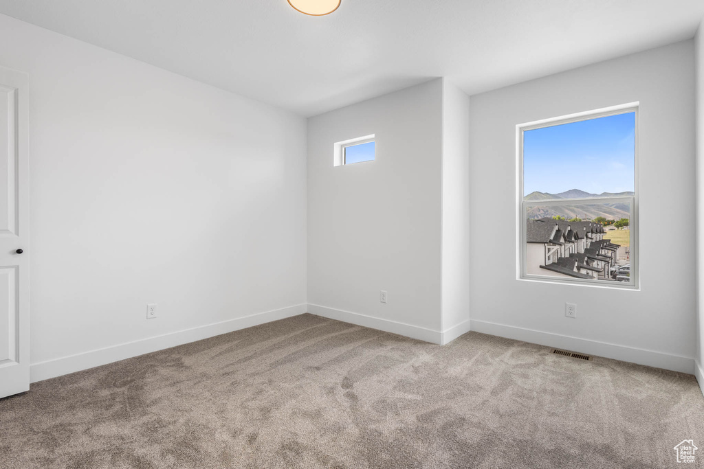 Spare room featuring carpet flooring and baseboards
