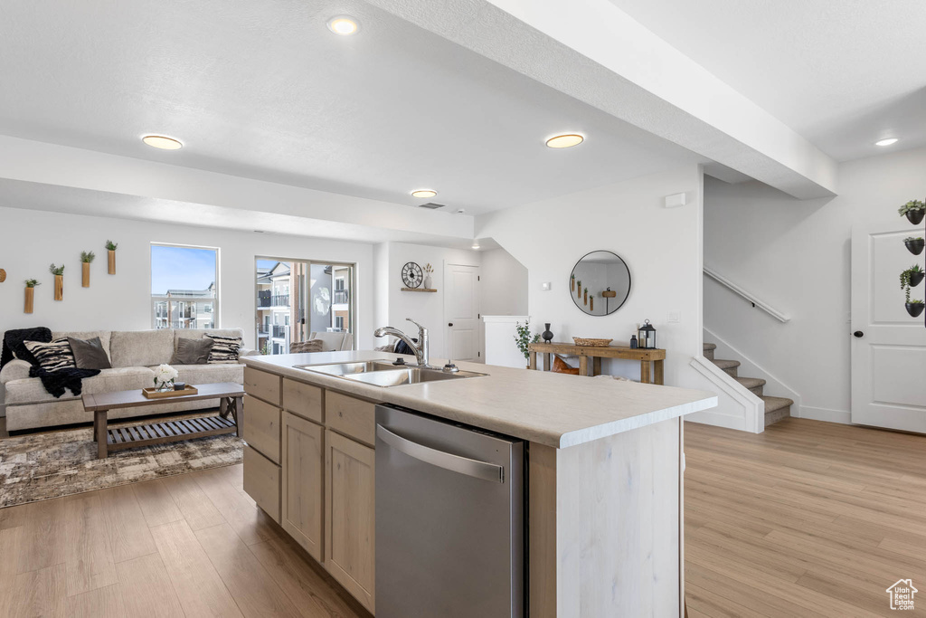 Kitchen featuring stainless steel dishwasher, a sink, light wood-type flooring, recessed lighting, and light countertops