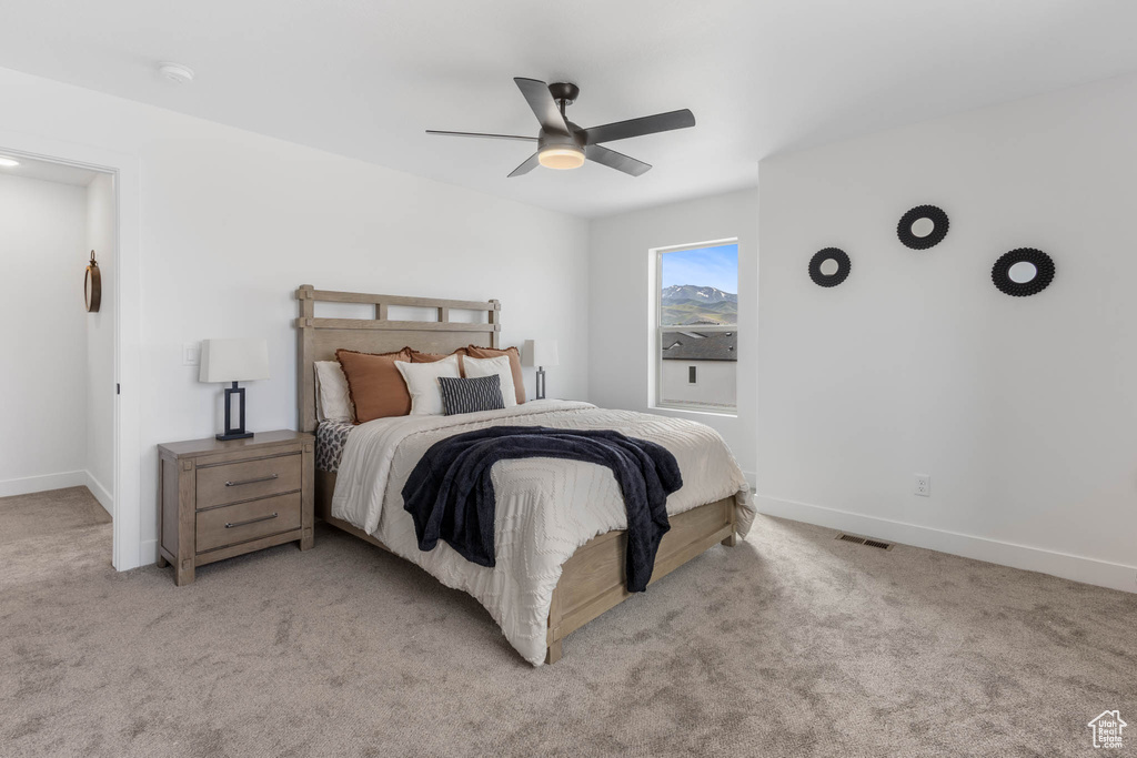 Bedroom with light colored carpet, baseboards, and ceiling fan