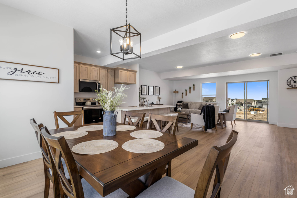 Dining room with baseboards, light wood-style floors, recessed lighting, and a chandelier