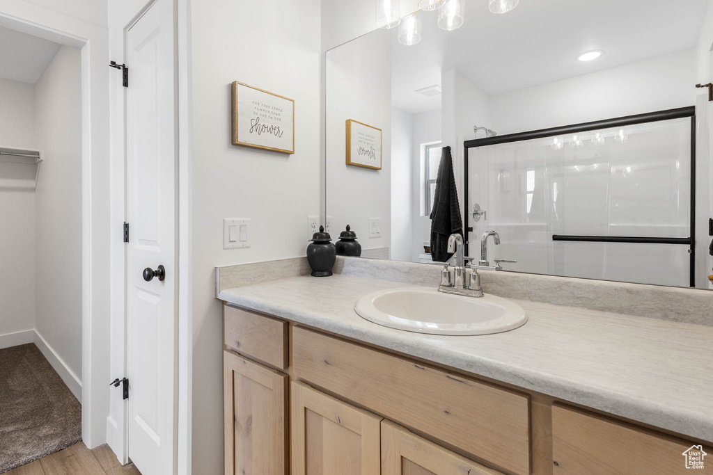 Full bathroom featuring vanity, a shower with door, a closet, and wood finished floors