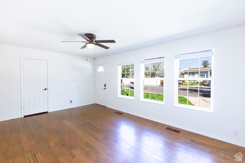 Spare room featuring ceiling fan, dark wood-type flooring, and baseboards