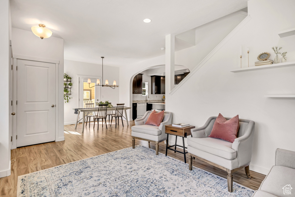 Living room featuring wood finished floors, arched walkways, a chandelier, baseboards, and recessed lighting