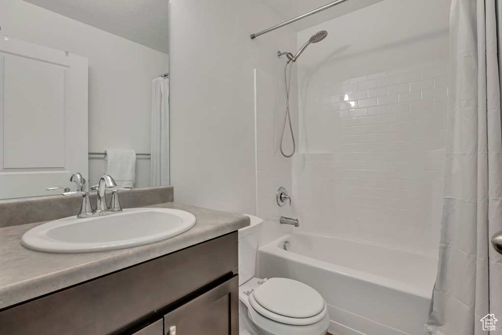Bathroom with shower / bath combo, vanity, and toilet