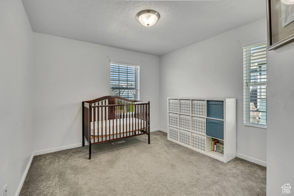 Carpeted bedroom with baseboards and a crib