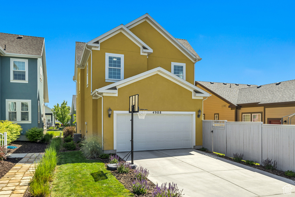 Traditional-style house featuring stucco siding, driveway, and a garage