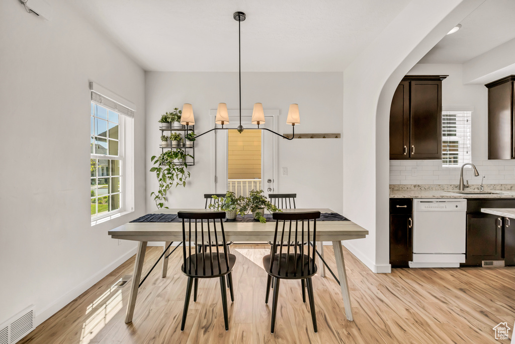 Dining space featuring light wood finished floors, baseboards, and arched walkways