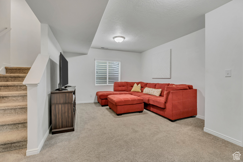 Living room featuring light carpet, baseboards, stairs, and a textured ceiling
