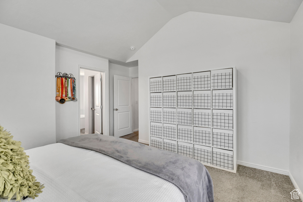 Bedroom with vaulted ceiling, baseboards, and carpet