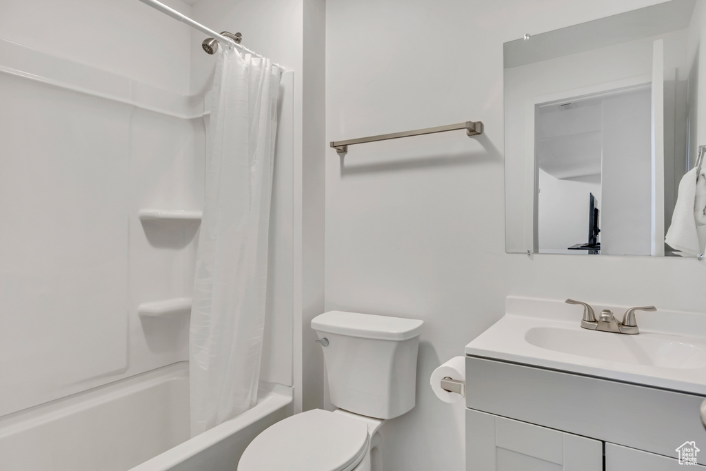 Bathroom featuring vanity, shower / bath combo with shower curtain, and toilet