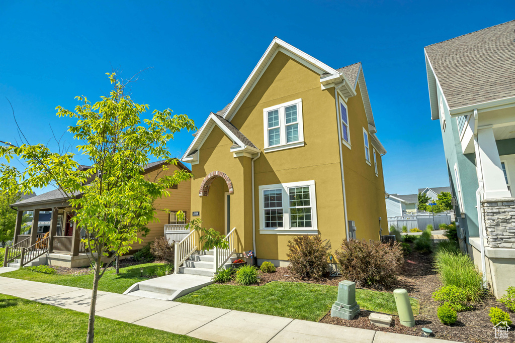 Traditional home with stucco siding, a front yard, and a porch