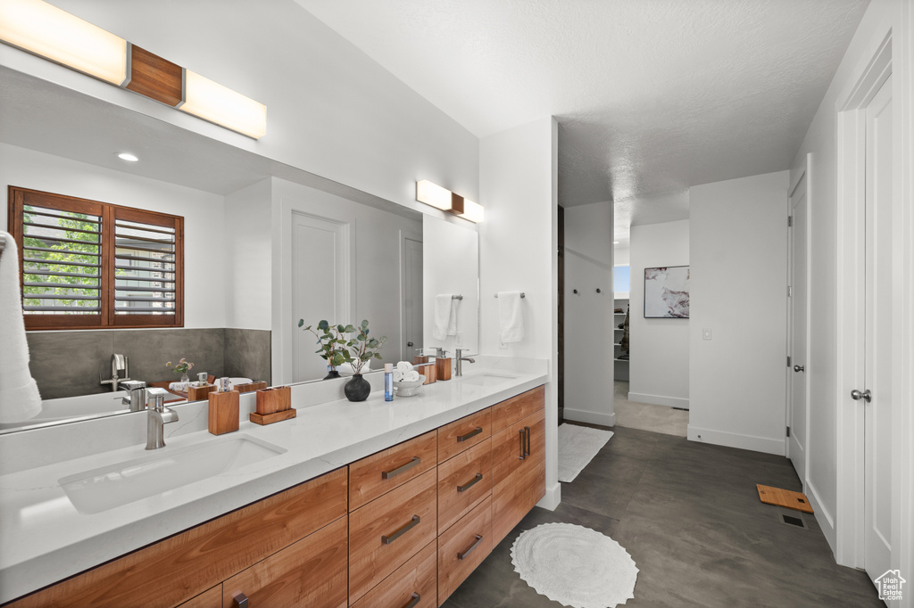 Full bathroom with double vanity and baseboards