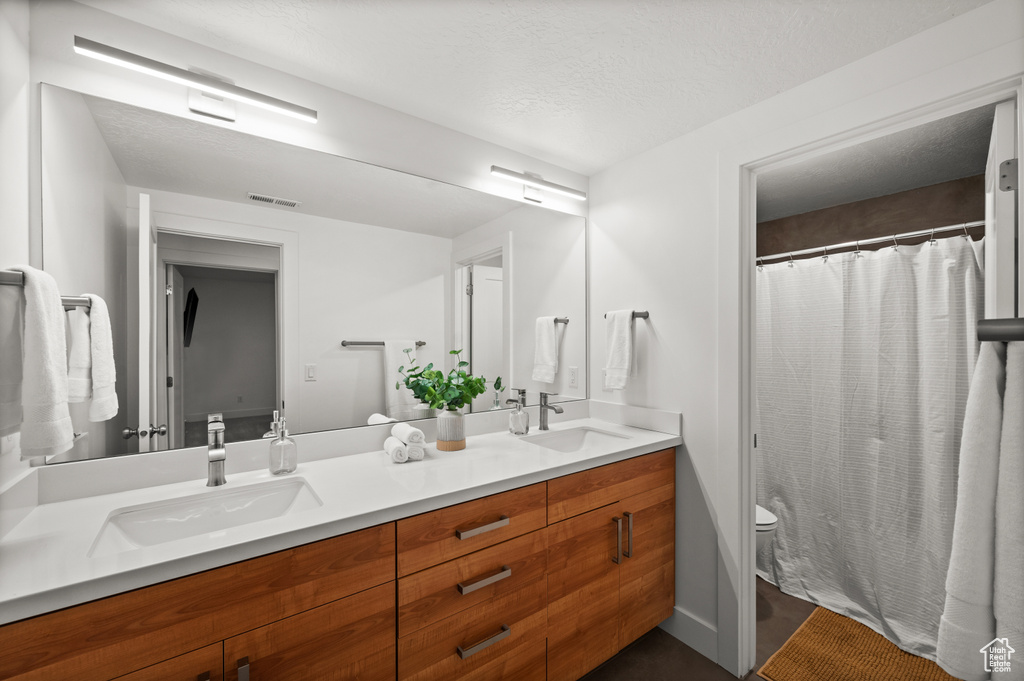 Full bath featuring toilet, double vanity, and a shower with curtain
