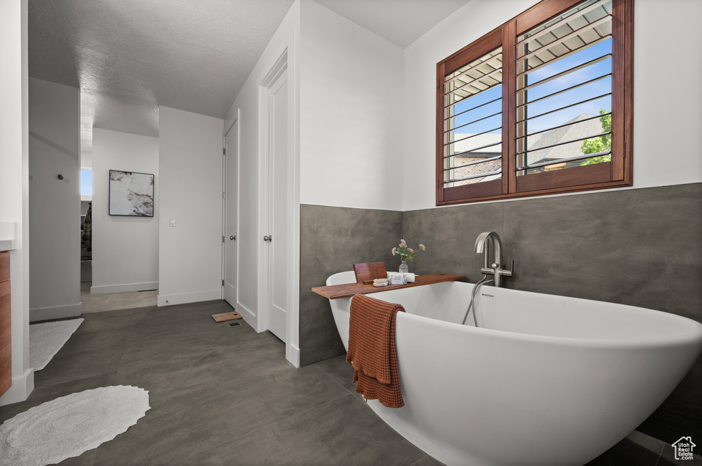 Full bathroom with finished concrete floors and a soaking tub