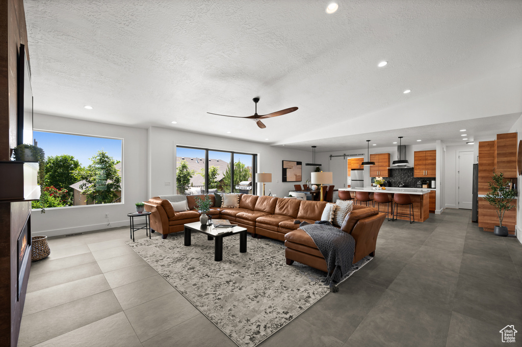 Living area featuring recessed lighting, ceiling fan, a textured ceiling, baseboards, and vaulted ceiling