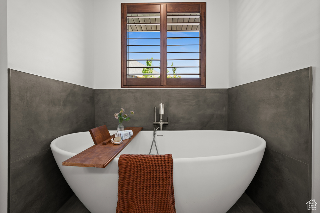 Bathroom featuring a soaking tub and tile walls