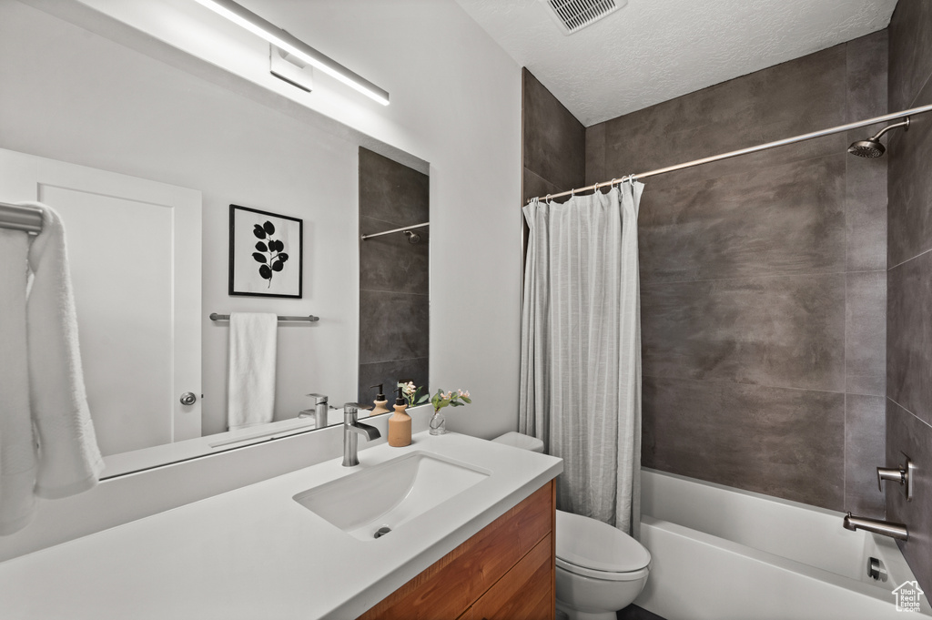 Full bathroom with vanity, shower / bathtub combination with curtain, and toilet