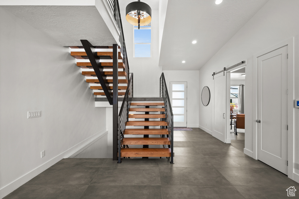 Entrance foyer with a barn door, stairs, recessed lighting, and baseboards