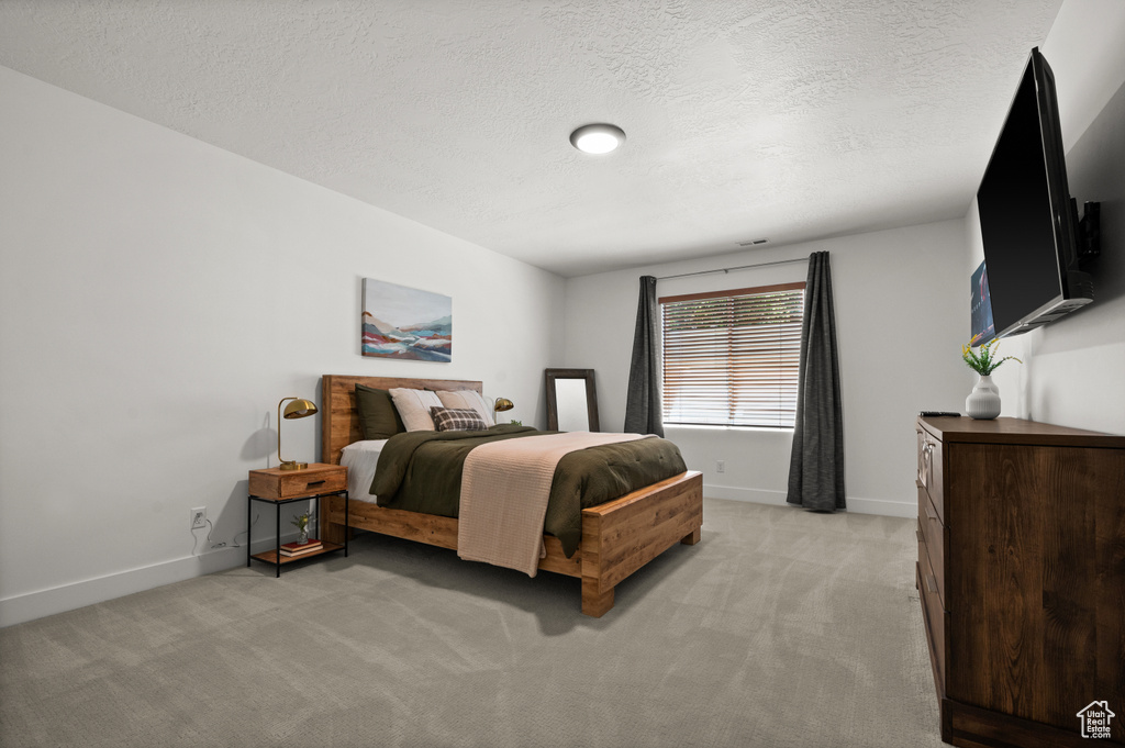 Bedroom with light colored carpet, baseboards, and a textured ceiling
