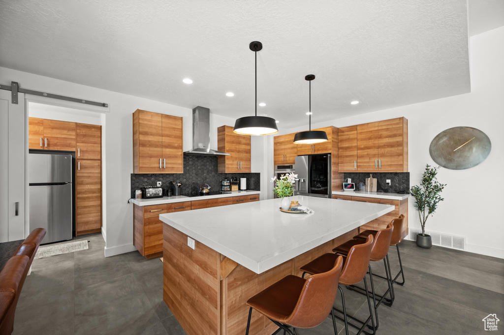 Kitchen with wall chimney range hood, freestanding refrigerator, stainless steel refrigerator with ice dispenser, baseboards, and backsplash