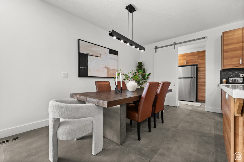 Dining space featuring a barn door, finished concrete floors, and baseboards