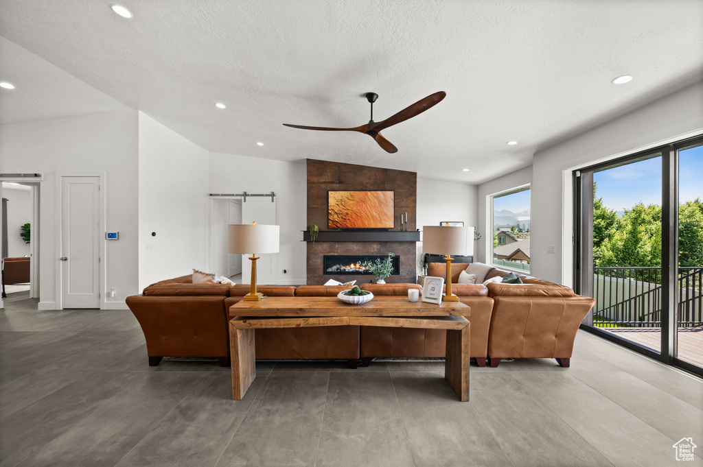 Living area with ceiling fan, recessed lighting, lofted ceiling, and a tile fireplace
