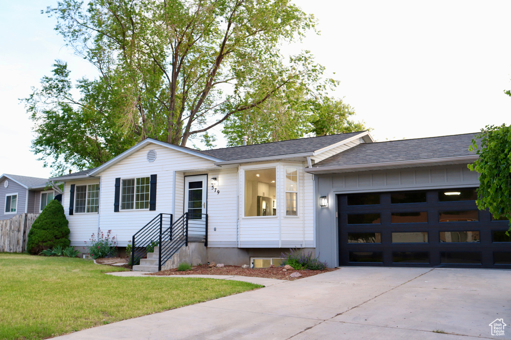 Single story home with driveway, an attached garage, a front lawn, and roof with shingles