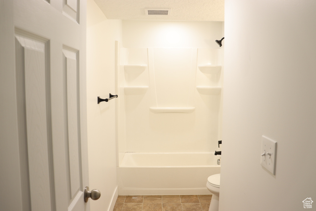 Full bathroom with toilet, baseboards, and shower / bathtub combination