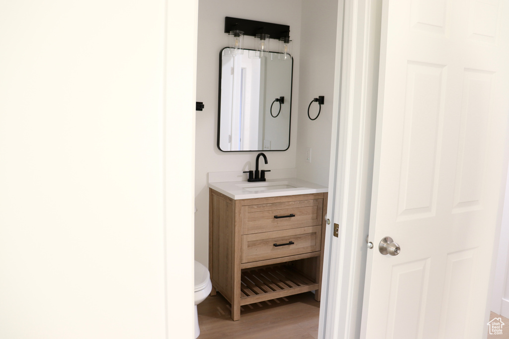 Bathroom featuring vanity, toilet, and wood finished floors