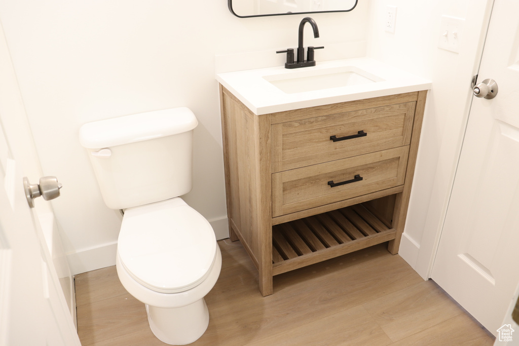 Bathroom with toilet, vanity, and wood finished floors