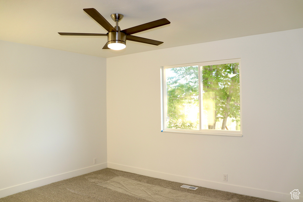 Empty room featuring light carpet, baseboards, and a ceiling fan