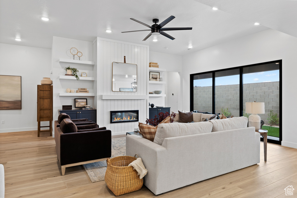 Living area with ceiling fan, light wood-style floors, recessed lighting, a large fireplace, and baseboards