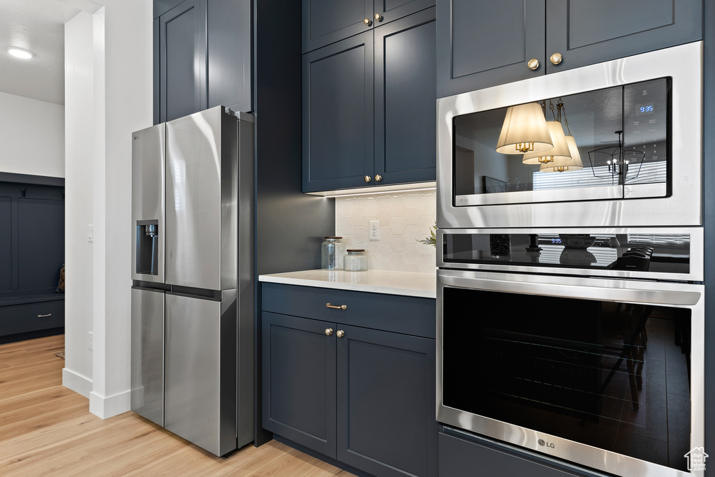 Kitchen with stainless steel appliances, light wood finished floors, tasteful backsplash, light countertops, and recessed lighting