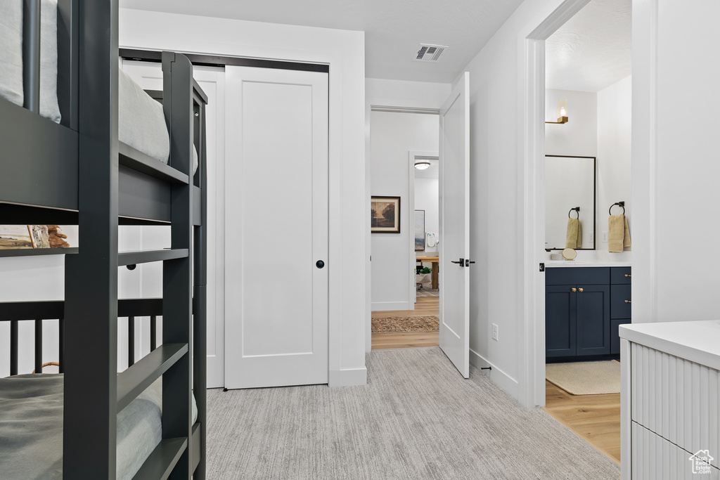Unfurnished bedroom with ensuite bathroom, baseboards, a closet, and light wood finished floors