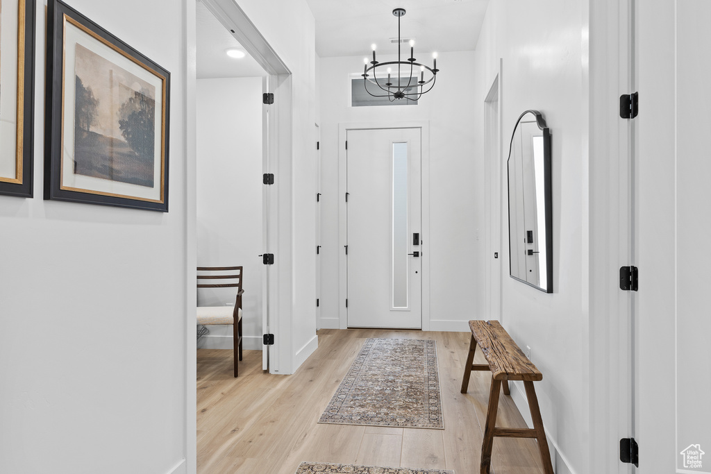 Foyer with a chandelier, light wood-type flooring, and baseboards
