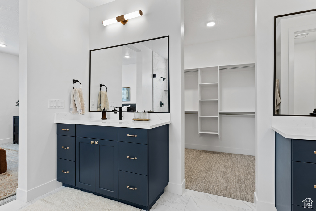 Full bath with vanity, a walk in shower, baseboards, and a spacious closet