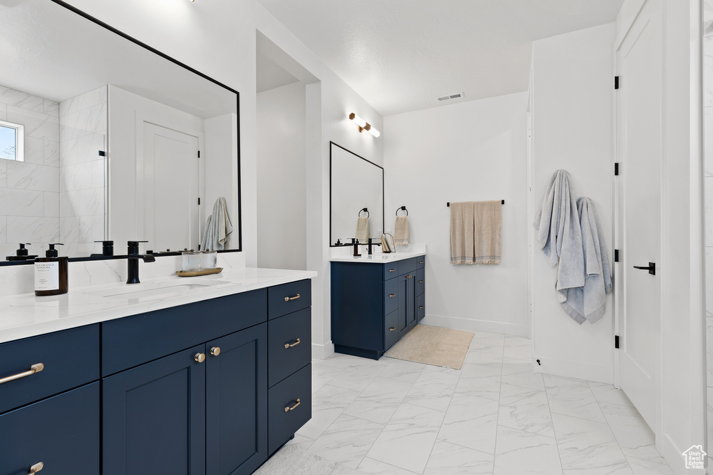 Full bathroom with two vanities, marble finish flooring, and baseboards