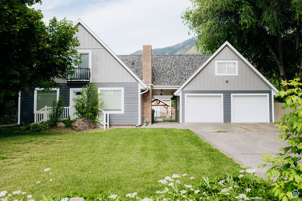 View of front of property featuring a balcony, a front lawn, a chimney, board and batten siding, and concrete driveway