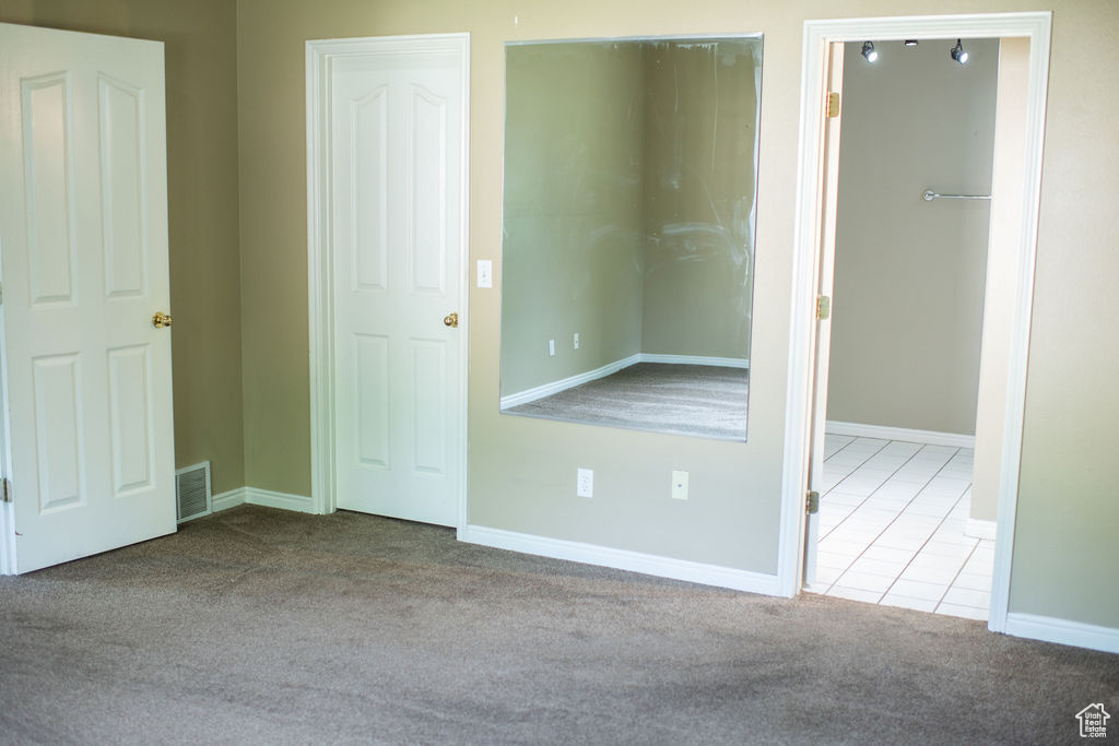 Unfurnished bedroom featuring carpet, baseboards, and tile patterned floors