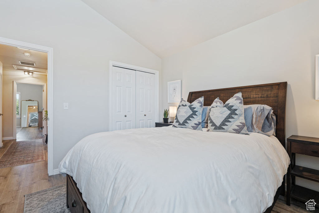 Bedroom featuring wood finished floors, baseboards, a closet, and high vaulted ceiling