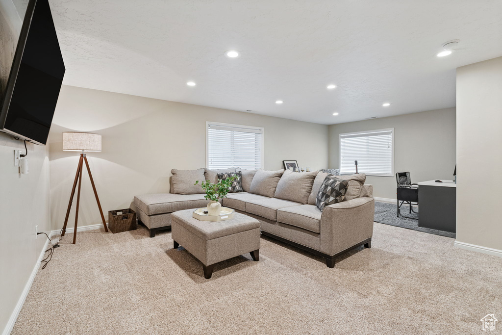 Living area with light colored carpet, baseboards, and recessed lighting