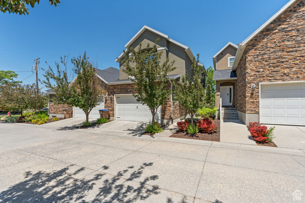 View of front of property with stone siding, driveway, and stucco siding